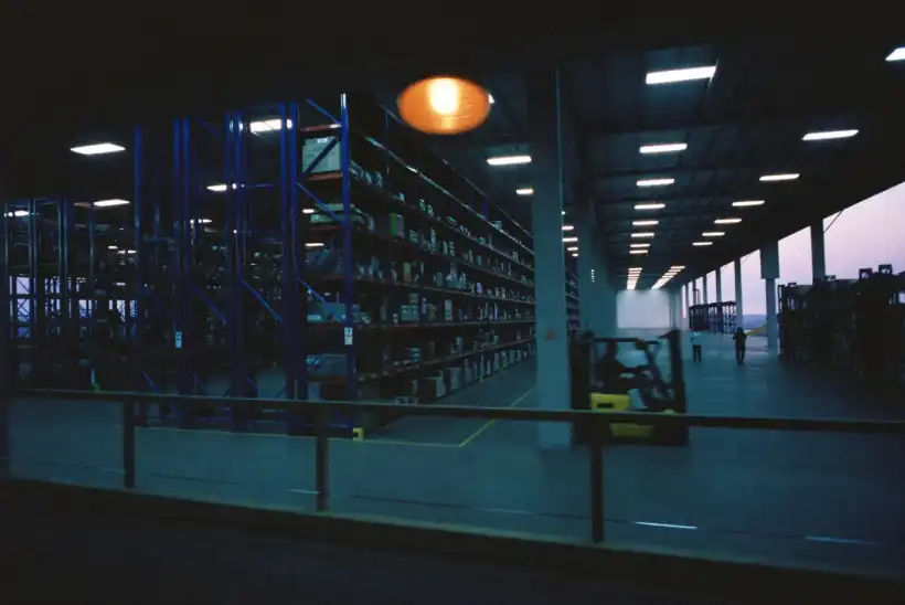 A distribution warehouse at dusk, racking receding into the distance and a forklift in motion